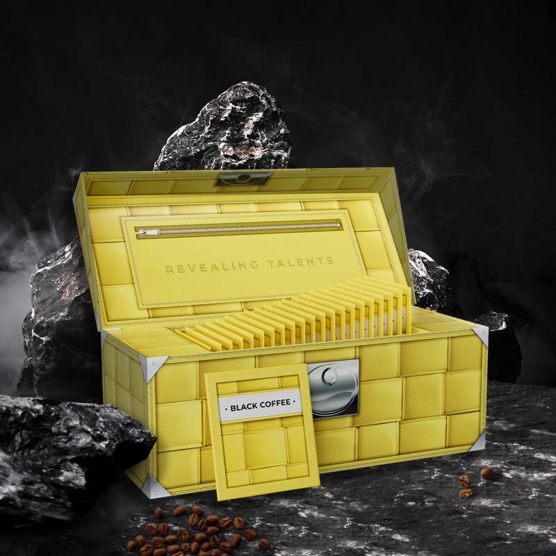 Открытая желтая коробка COFFEECELL с черным кофе на камнях